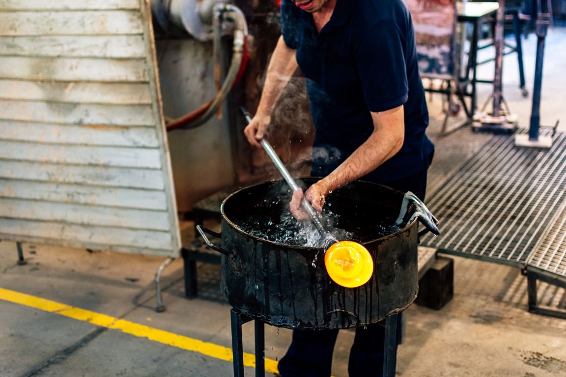 glassworks glass manufacturing. glass artisan working on a piece of hot glass.