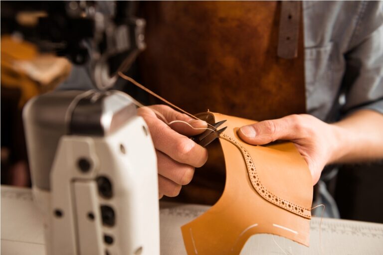man artisan sewing leather shoes indoors at a workshop