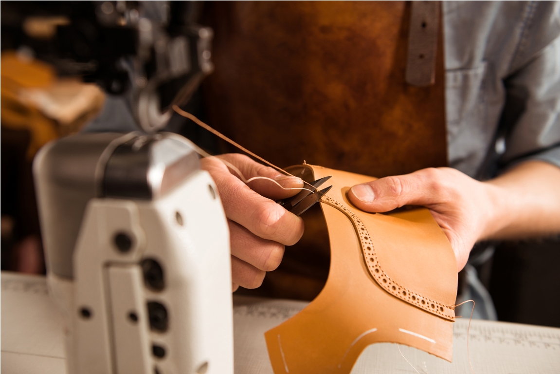 man artisan sewing leather shoes indoors at a workshop