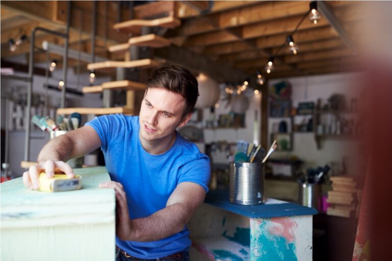 man in workshop upcycling and working on furniture with sandpaper