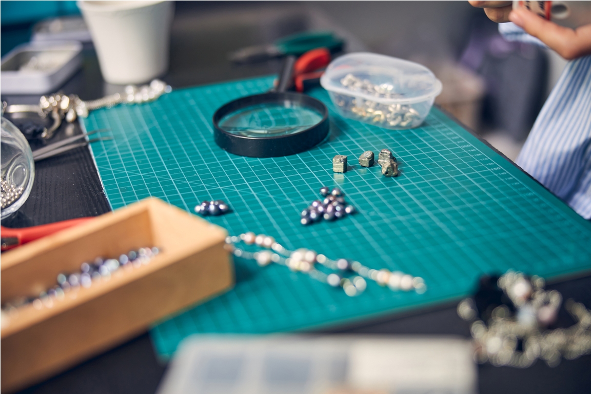 stones and beads lying on measurement surface with jewelry tools