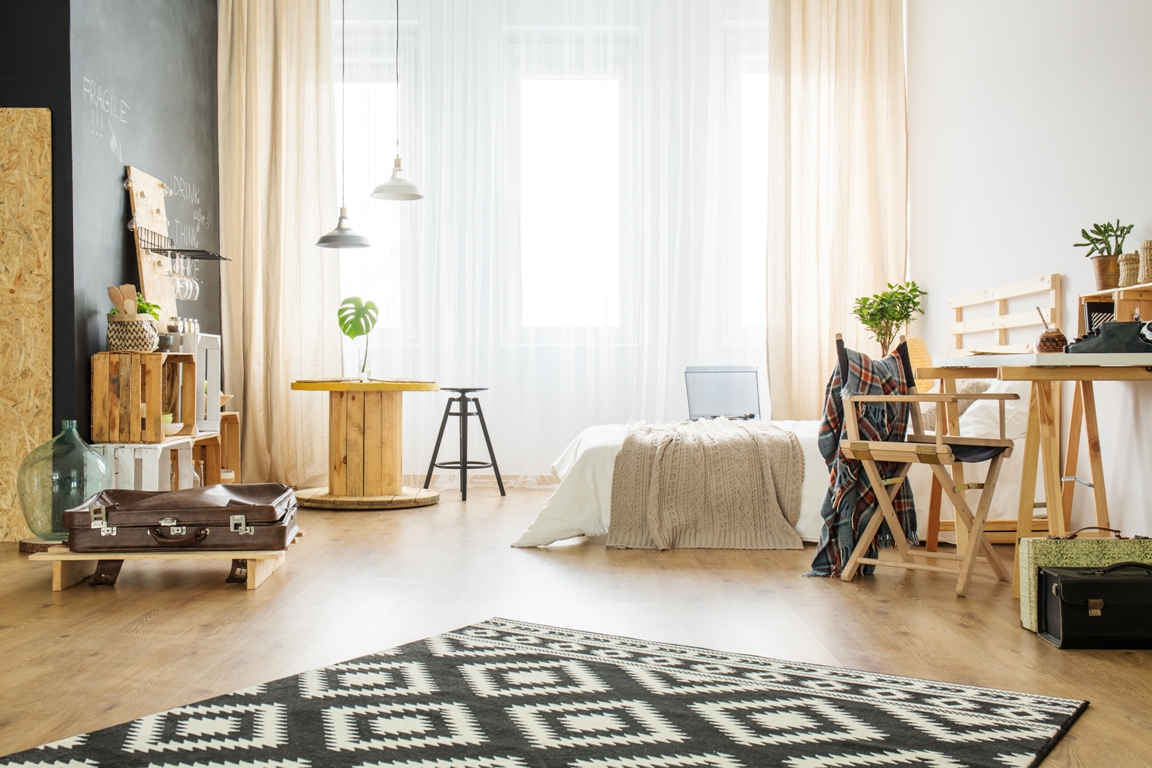 creative interior of upcycled studio apartment with bed and wooden furniture