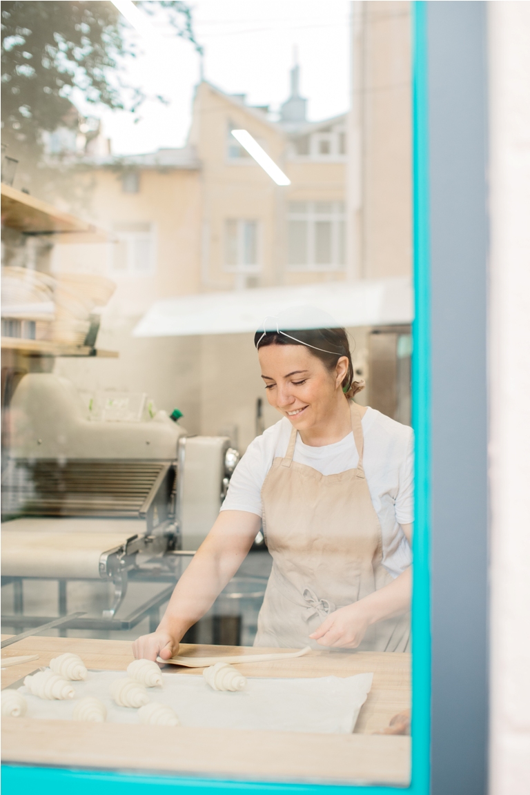 woman baker making croissants in bakery standing in front of window.